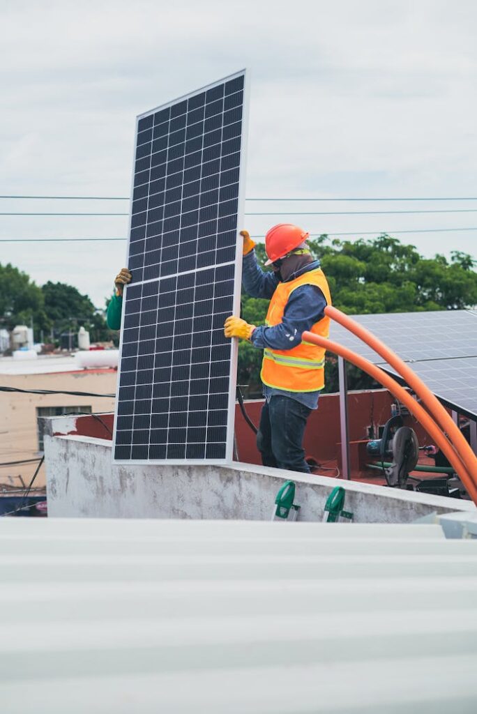 pexels-photo-8853504 A technician in safety gear installs a solar panel on a rooftop, promoting renewable energy.
