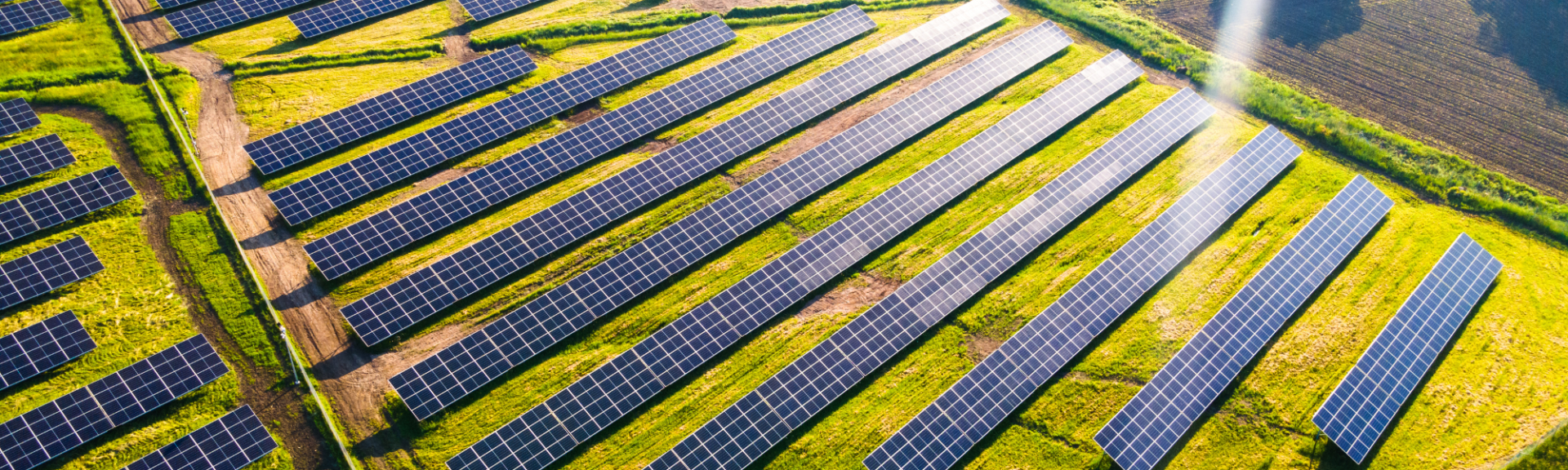 Worker in safety gear installing solar panels on a rooftop.